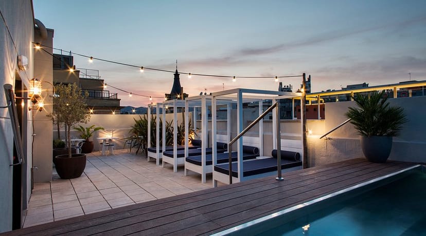 Rooftop hotel cocktail reception with string lights and lounge seating for VIP networking events.