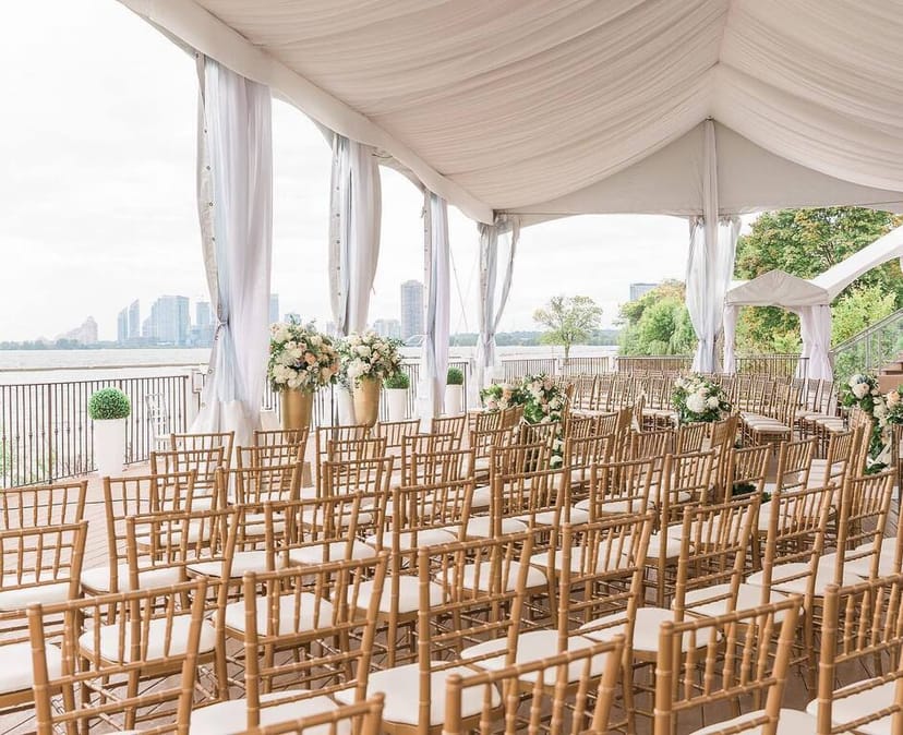 Courtyard patio wedding ceremony at Palais Royale with waterfront skyline and gold Chiavari chairs.