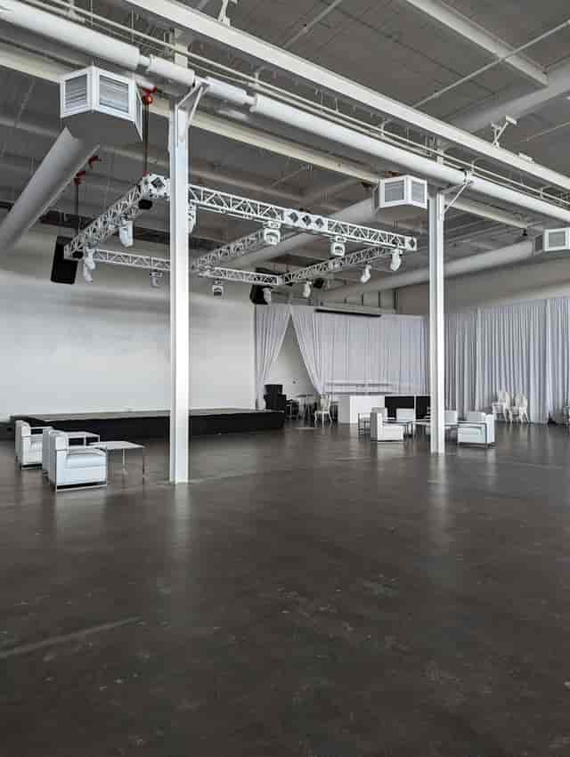 Industrial-chic warehouse event venue with truss system for corporate events and networking.
