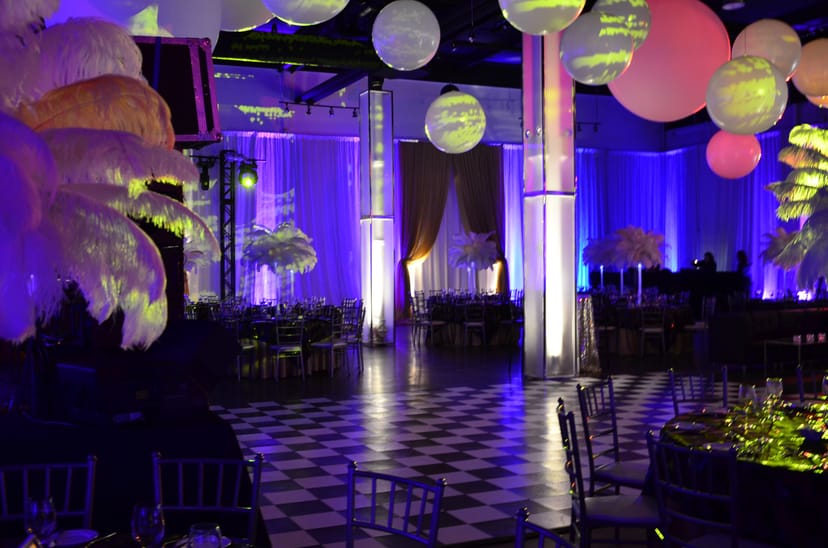 Gala banquet hall at The Warehouse with dramatic lighting and feather centerpieces for events.