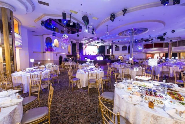 Ballroom banquet hall with cabaret seating and stage for gala and wedding event venue.