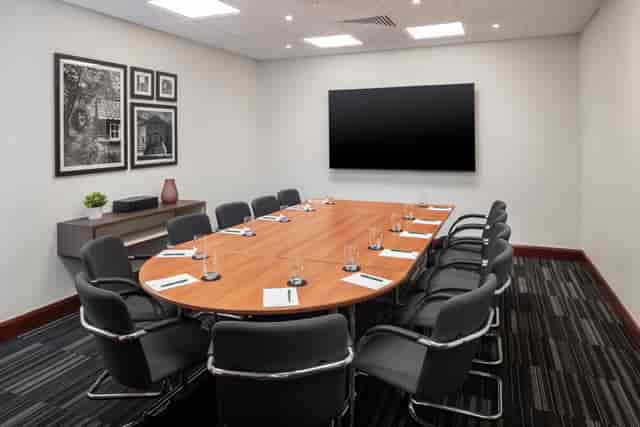 Meeting room at Holiday Inn London-Bexley, featuring an oval table and presentation screen.