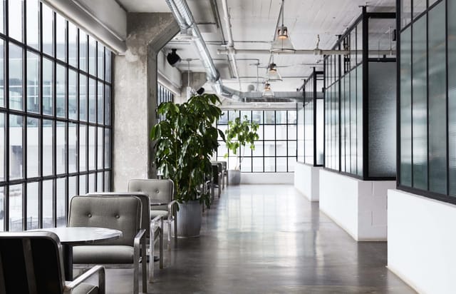 Industrial-chic East Room social club with natural light for corporate retreats and networking.