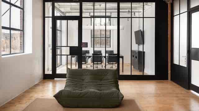 Modern industrial breakout space with glass boardroom for corporate meetings and networking.