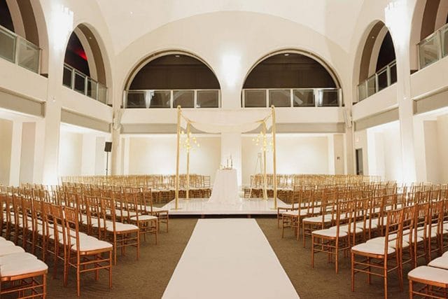 Arcadian Loft wedding ceremony with arched windows and symmetrical venue decor.