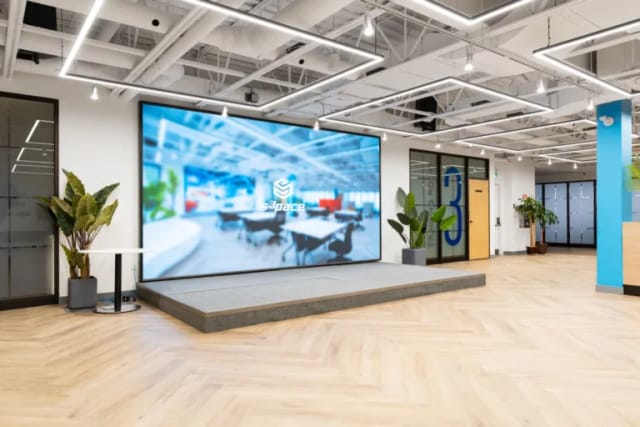 Modern media room with LED wall and stage for corporate town halls and product demo events.