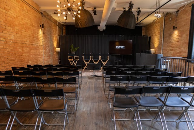 Industrial-chic theater venue with exposed brick for corporate offsite meetings and presentations.