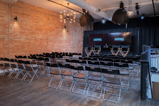 Industrial-chic studio with exposed brick for fireside chats and hybrid event panel discussions.