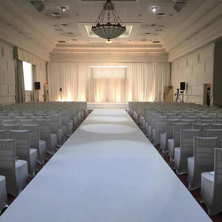 Elegant wedding ballroom with symmetrical aisle and uplighting for wedding ceremony venue.