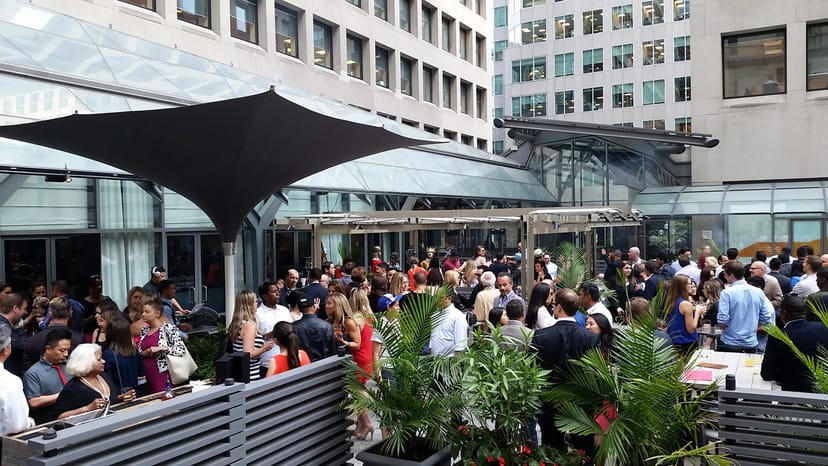 Outdoor corporate networking mixer on a sheltered urban patio.
