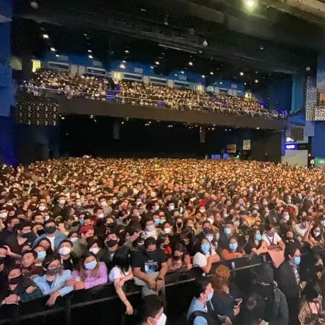 Crowded Pepsi Center ballroom concert with safety barricades, live music event venue.