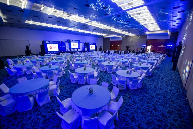 Centro Banamex ballroom, gala banquet setup with blue LED lighting and triple-screen AV staging.