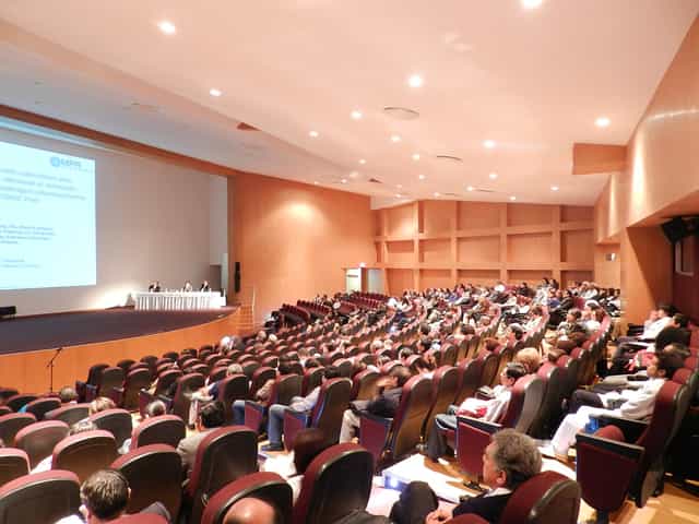 Plenary session at Cinia Gonzalez Diez auditorium, featuring tiered seating and stage presentation.