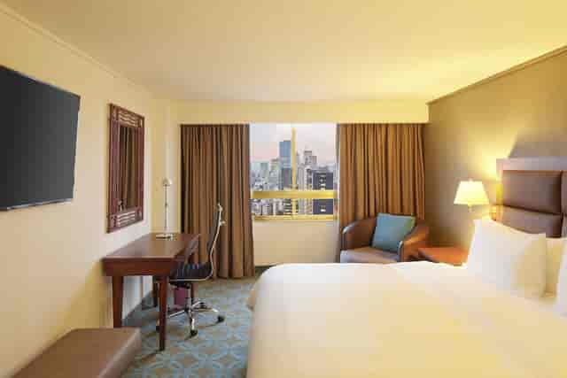 Hotel guest room with ergonomic workspace and city view for business travel and conferences.