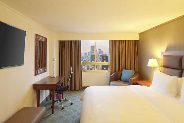 Hotel guest room with ergonomic workspace and city view for business travel and conferences.