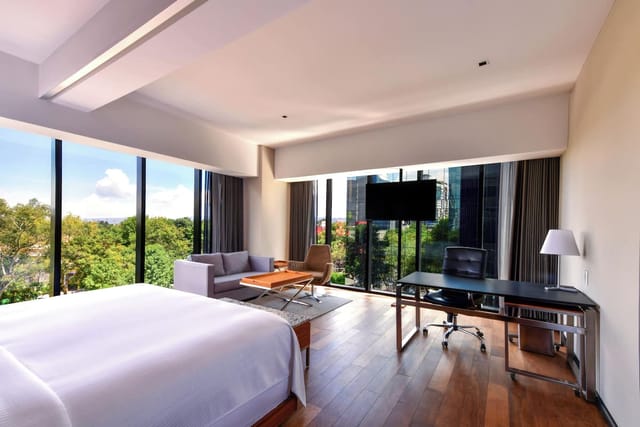 Modern guest room with workspace and floor-to-ceiling windows for business travel meetings.