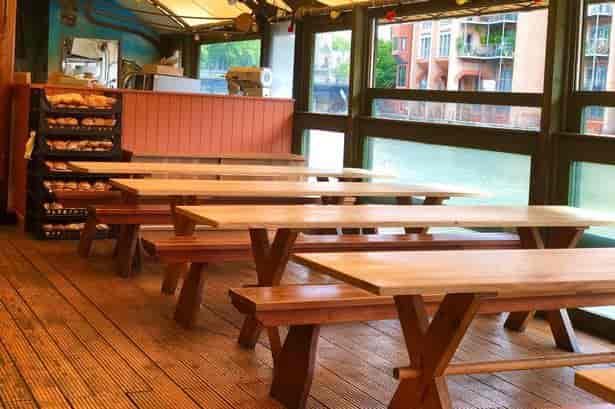 Rustic waterfront dining area with communal seating for casual events and team building.