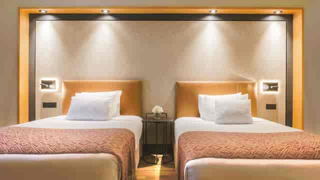 Twin hotel room with modern decor for corporate event blocks and business travel accommodation.