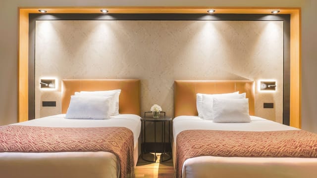 Twin hotel room with modern decor for corporate event blocks and business travel accommodation.