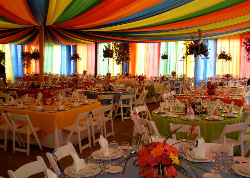 Thematic tent banquet hall with vibrant ceiling draping for colorful event and wedding venues.