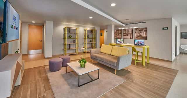 City Express Suites Mexico City event breakout space with lounge seating and workstations.