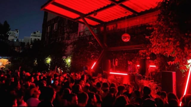 Outdoor nightlife event at Jardín Juárez with red lighting, DJ setup, and packed dance floor.