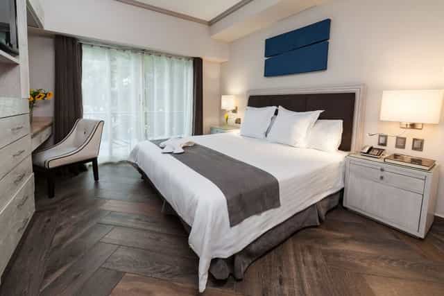 Modern hotel suite with desk for business travel and corporate event room blocks.