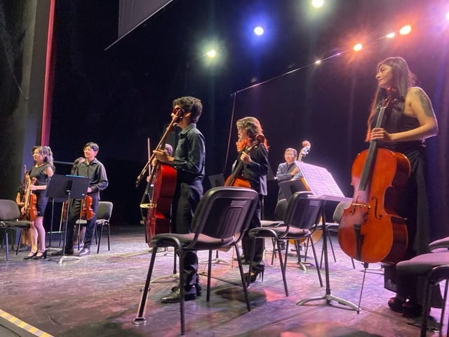 Chamber music ensemble performing on stage under theatrical lighting for cultural event venue.