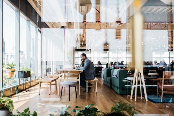 Modern WeWork dedicated desk in a light-filled open office for networking and breakout sessions.