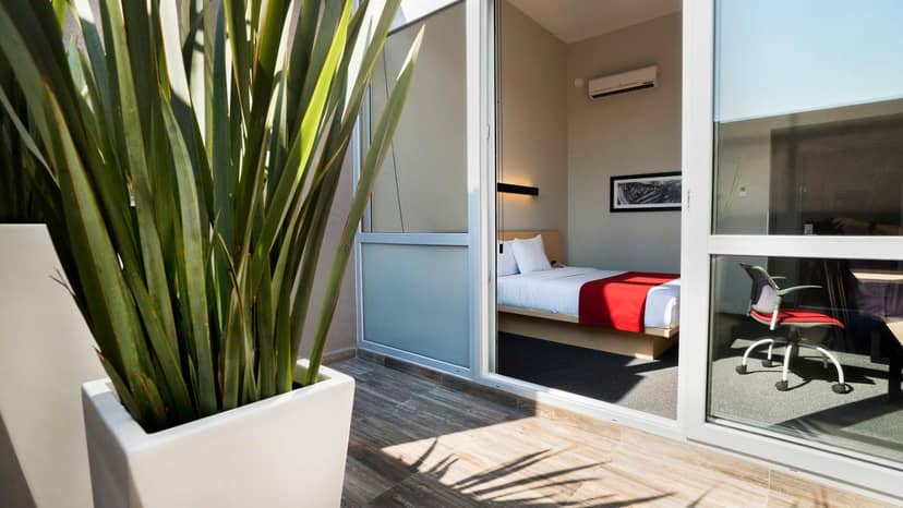 Bleisure hotel room with ergonomic workspace at City Express Plus Mexico, ideal for business events.