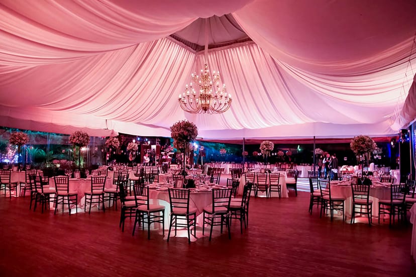 Luxury gala marquee with crystal chandeliers and pink lighting for upscale wedding events.