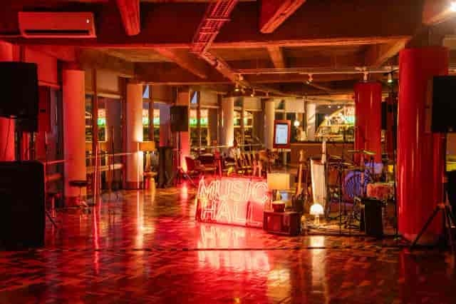 Industrial-chic event hall with red lighting, perfect for live music and corporate concert venues.