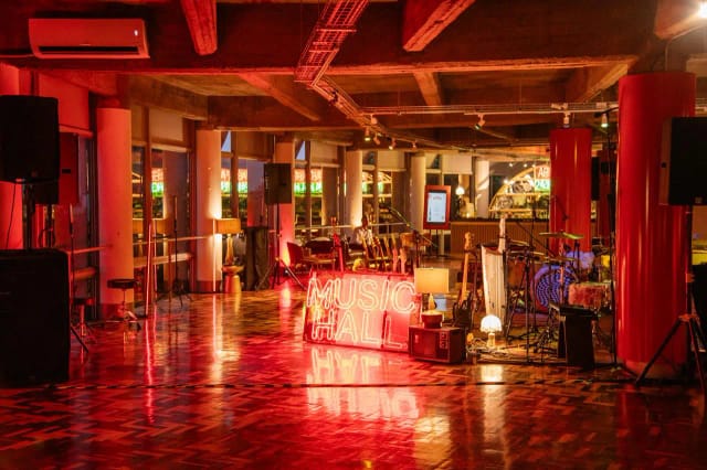 Industrial-chic event hall with red lighting, perfect for live music and corporate concert venues.