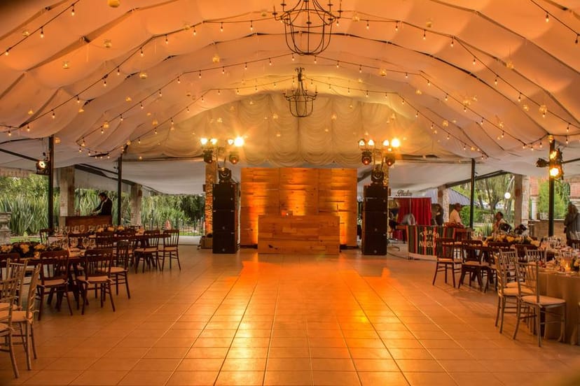 Draped open-air tent venue with dance floor for wedding and corporate event receptions.
