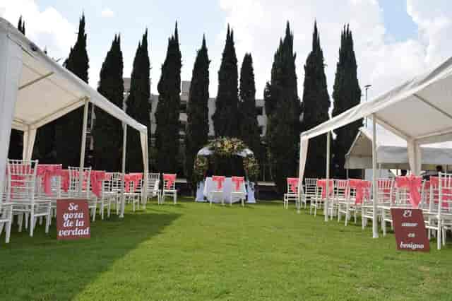 Outdoor wedding ceremony with Chiavari chairs at Salón y Jardín Los Pinos garden venue.