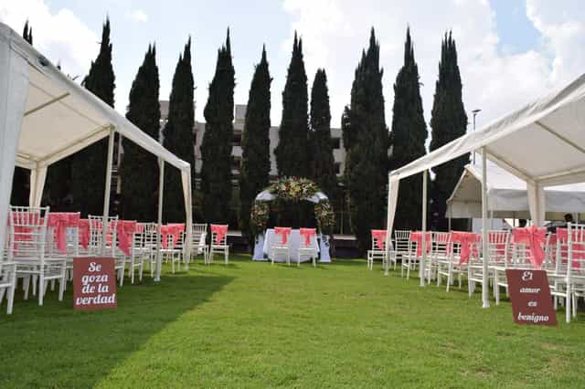 Outdoor wedding ceremony with Chiavari chairs at Salón y Jardín Los Pinos garden venue.