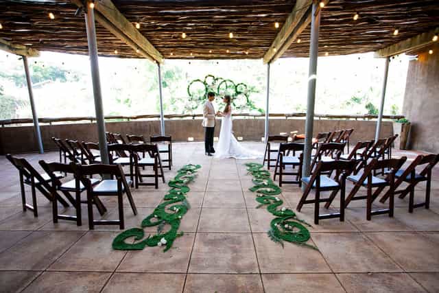 Rustic outdoor wedding ceremony at San Antonio Zoo Hippo Overlook with bistro-lit pergola.