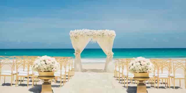 Avalon Ballroom beach wedding with floral arch and gold chairs for luxury destination events.