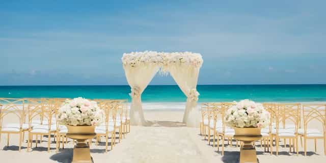 Avalon Ballroom beach wedding with floral arch and gold chairs for luxury destination events.