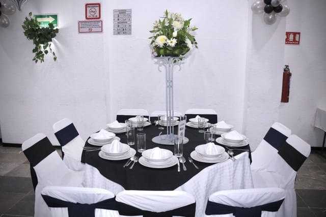 Salones Amarilis convention center event setup with monochromatic decor and floral centerpiece.