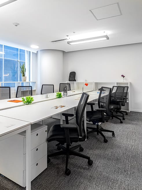 Minimalist coworking breakout room with long tables for workshops and office meetings.