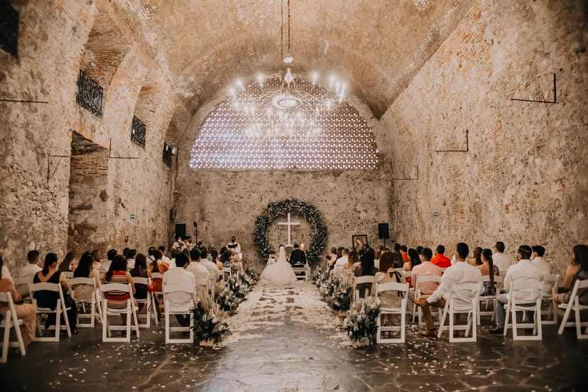 Luxury wedding ceremony in stone-walled Hacienda Vista Hermosa venue with dramatic chandeliers.