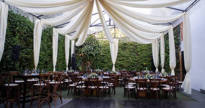 Elegant outdoor banquet hall with green-wall backdrop for sophisticated event venue dining.