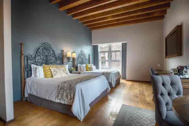 Upscale double hotel room with rustic beams and wrought-iron for VIP speaker event accommodations.