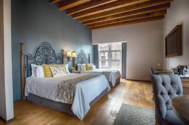 Upscale double hotel room with rustic beams and wrought-iron for VIP speaker event accommodations.