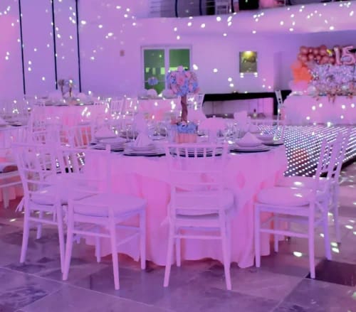 Purple-lit ballroom with Chiavari chairs and dance floor for Quinceañera or formal celebration.