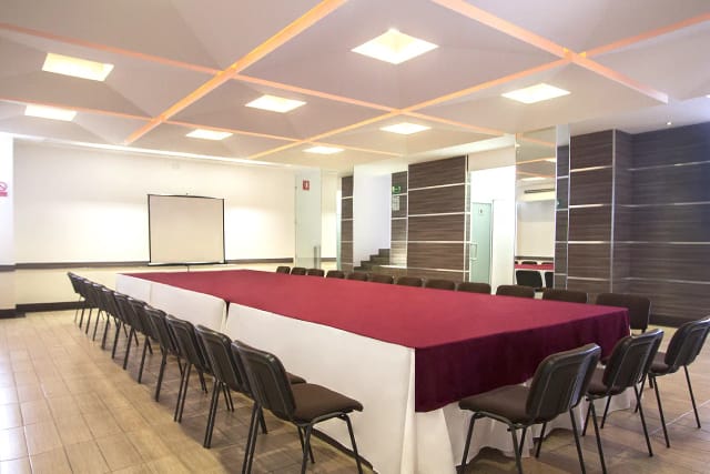 Salón Orizaba boardroom setup with red table for corporate meetings and business events.