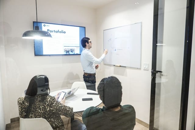 Modern huddle room with digital display and whiteboard for collaborative brainstorming sessions.