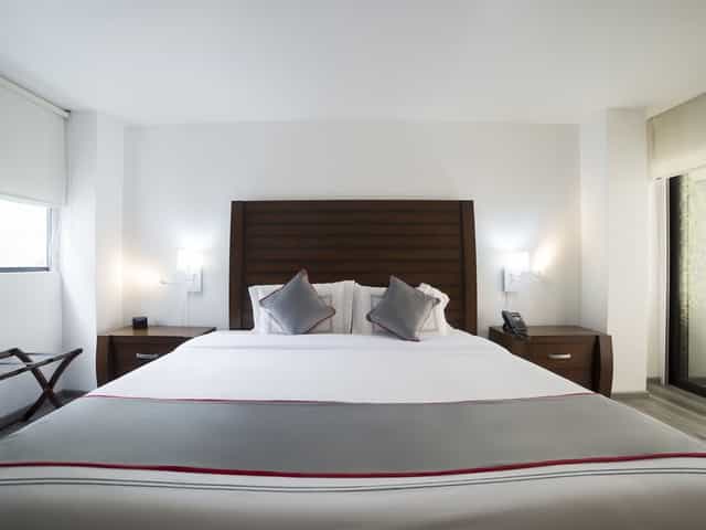 Hotel room at Suites Arboleda 215, minimalist design for business travel and conference lodging.