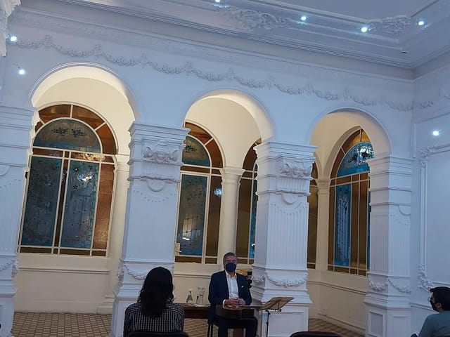 Architectural panel discussion at Casa del Tiempo with ornate arched windows for event venue.